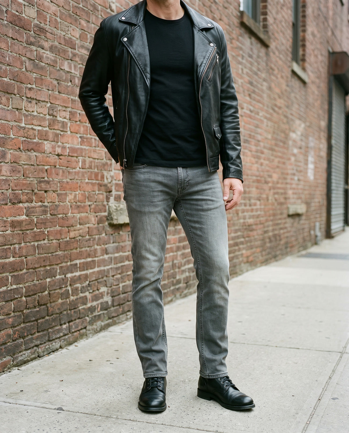 Oklahoma Jeans R140 Dark Grey mit schwarzer Lederjacke vor einer Backsteinwand